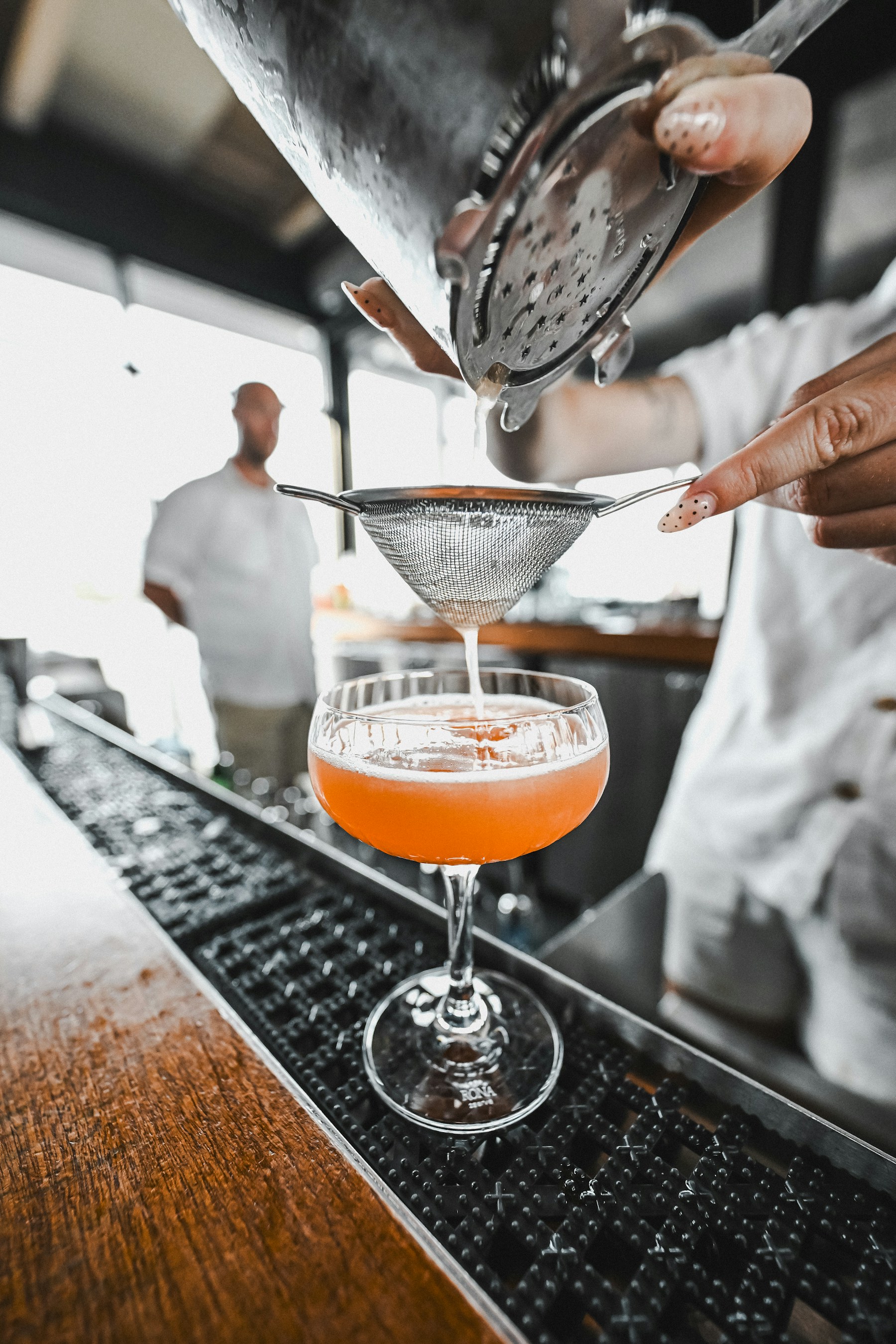 Bartender straining a fresh cocktail at the bar